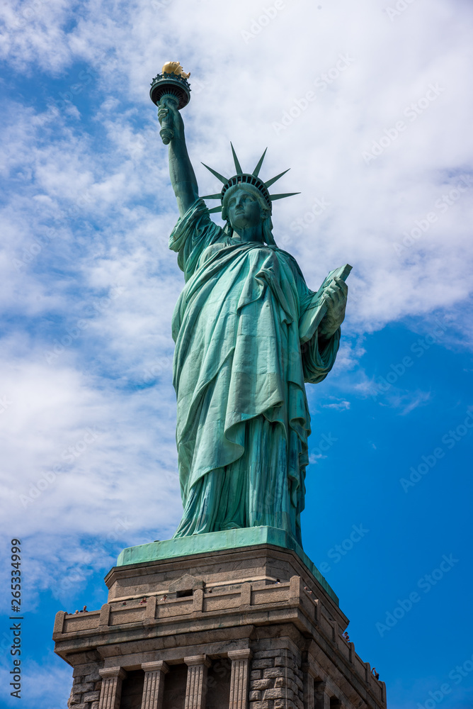 Naklejka premium Shot of the Statue of Liberty in New York City, Usa. The shot is taken during a beautiful sunny day with a blue sky and white clouds in the background