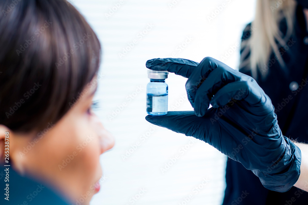 The doctor shows the injection to the patient. Bottle of medicine close-up. The doctor shows the injection to the patient. Bottle of medicine close-up.