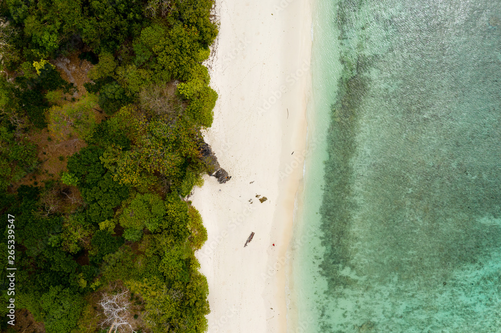 Aerial drone view of a deserted, idyllic tropical sandy beach on a small, lush green island