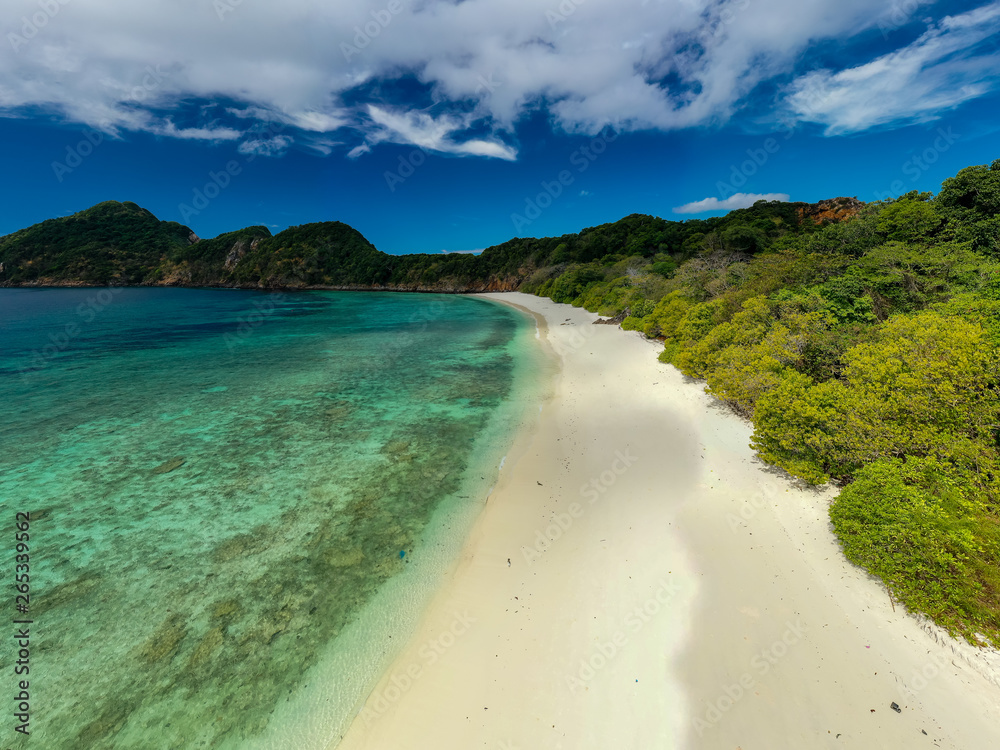 Aerial drone view of a lush, green tropical island with sandy beach