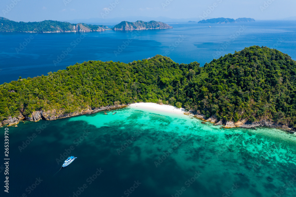Aerial drone view of a boat moored off a beautiful, deserted tropical island