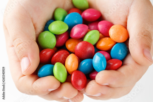 Multicolored candies in the hands of a child on a white isolated background