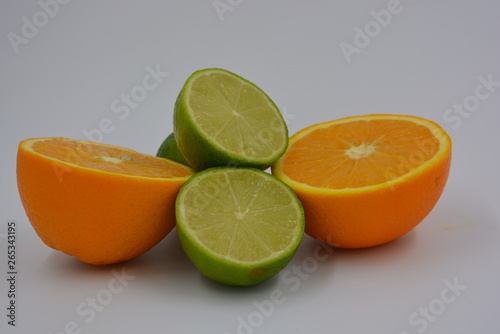 Bright two orange halves of sliced ​​ripe and juicy orange with lime fruits. Healthy food and fruit, health and sport.