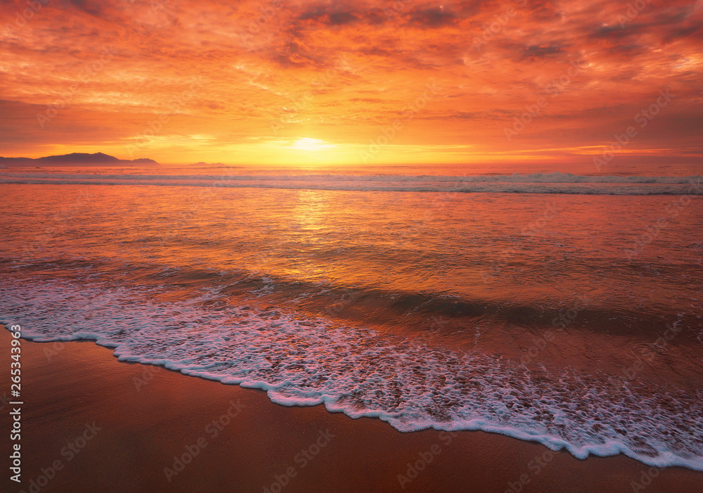 beautiful red sunset on beach with a wave on the shore - obrazy, fototapety, plakaty 