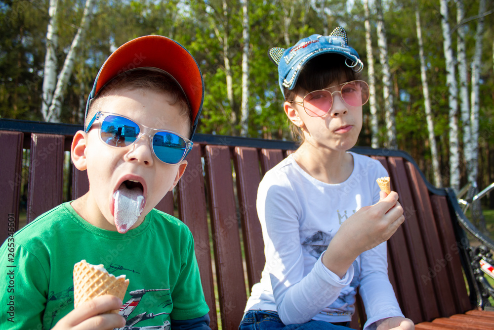 happy boy and girl eat ice cream in the park on the bench happy boy and girl eat ice cream in the park on the bench