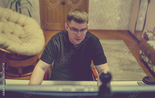 Freelancer working on computer at home Young concentrated man in glasses using computer while working in living room