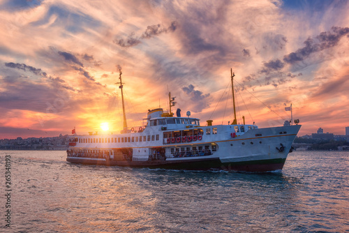 Amazing color sunset over Bosphorus with passenger boat (river tram) and sun, Istanbul, Turkey. Scenic travel background © larauhryn