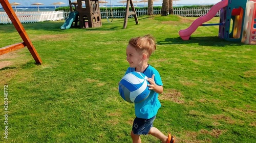 4k video of cheerful little boy running and playing with ball on th eplayground at park photo