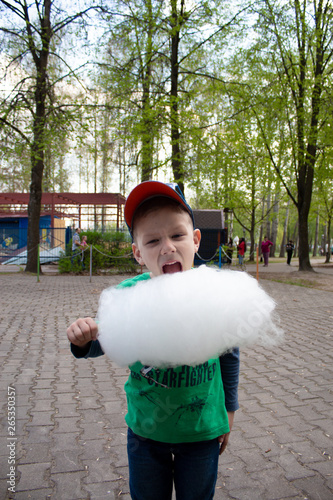 happy boy eating cotton candy in the park