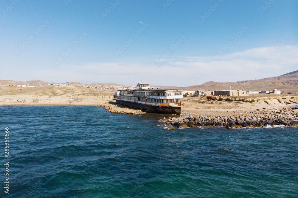 Old vintage abandoned rusted ship run aground after shipwreck long time ago sea coast on sand beach, aerial view