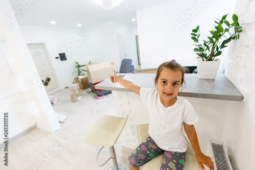 The happy little girl sits in a room boxes. Moving, purchase of new habitation or repair of a room.