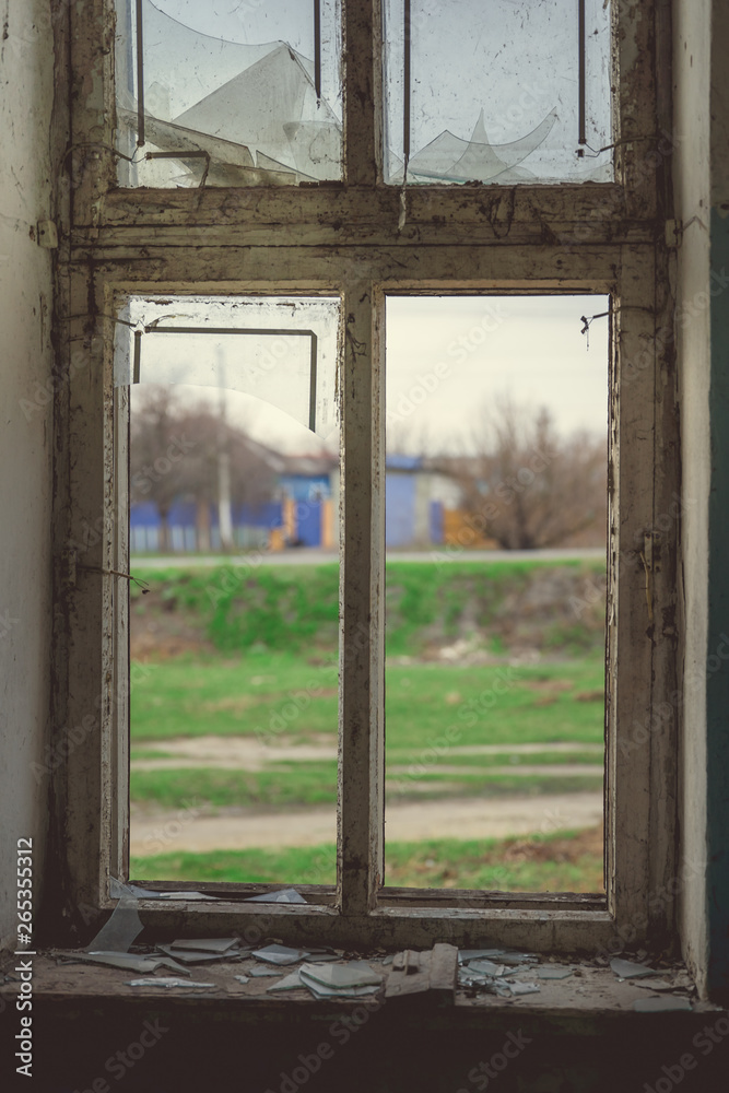 Window with broken glass in old building Wooden window frame with partially broken glass in old abandoned brick building Window with broken glass in old building Wooden window frame with partially broken glass in old abandoned brick building