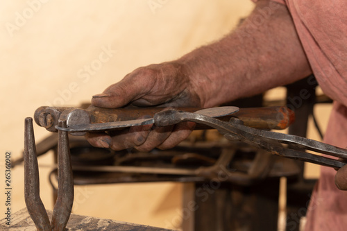 The hands of a traditional blacksmith shape a spoon from a bar of iron. 