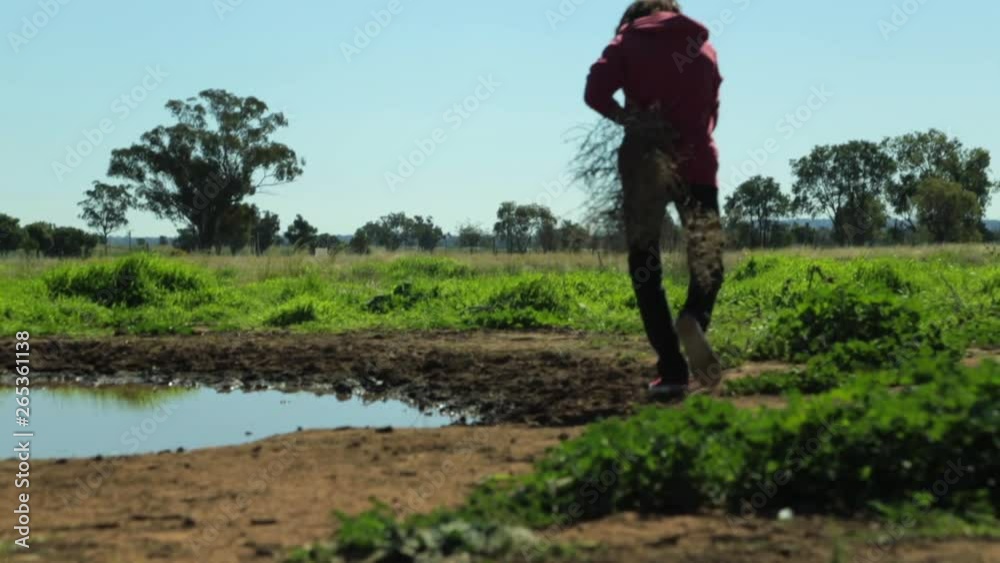 A long shot of a man walking around a gigantic puddle, mimicking the walk of an emu. A long shot of a man walking around a gigantic puddle, mimicking the walk of an emu.
