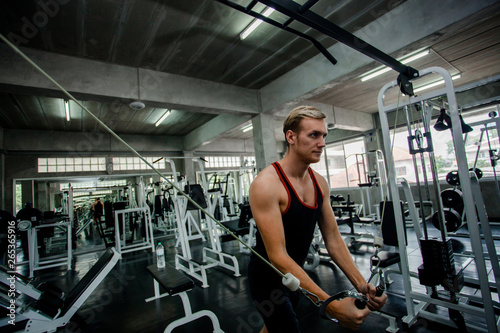 Fototapeta Naklejka Na Ścianę i Meble -  portrait of sporty girl workout on exercise machine in gym. Pretty young man training in the gym