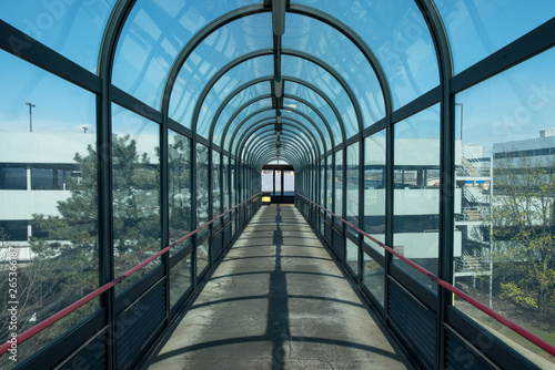 Abstract industrial outdoor covered walkway glass tunnel. Pedestrian bridge walkway tunnel. Glass and steel design and detail. 