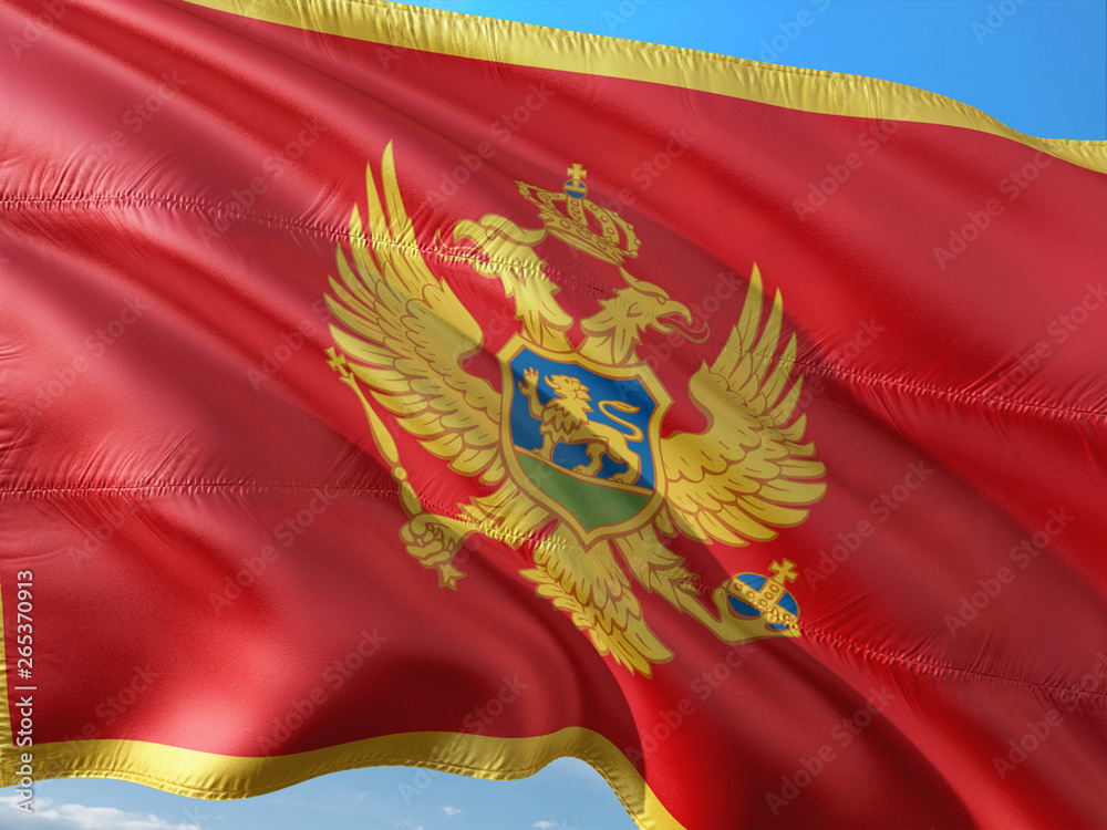 Flag of Montenegro waving in the wind against deep blue sky. High quality fabric.