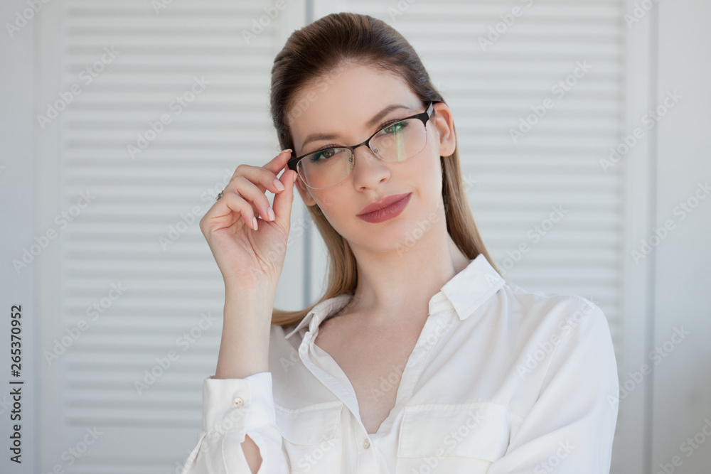 Portrait of a young stylish business woman in a white shirt and glasses. Portrait of a young stylish business woman in a white shirt and glasses.