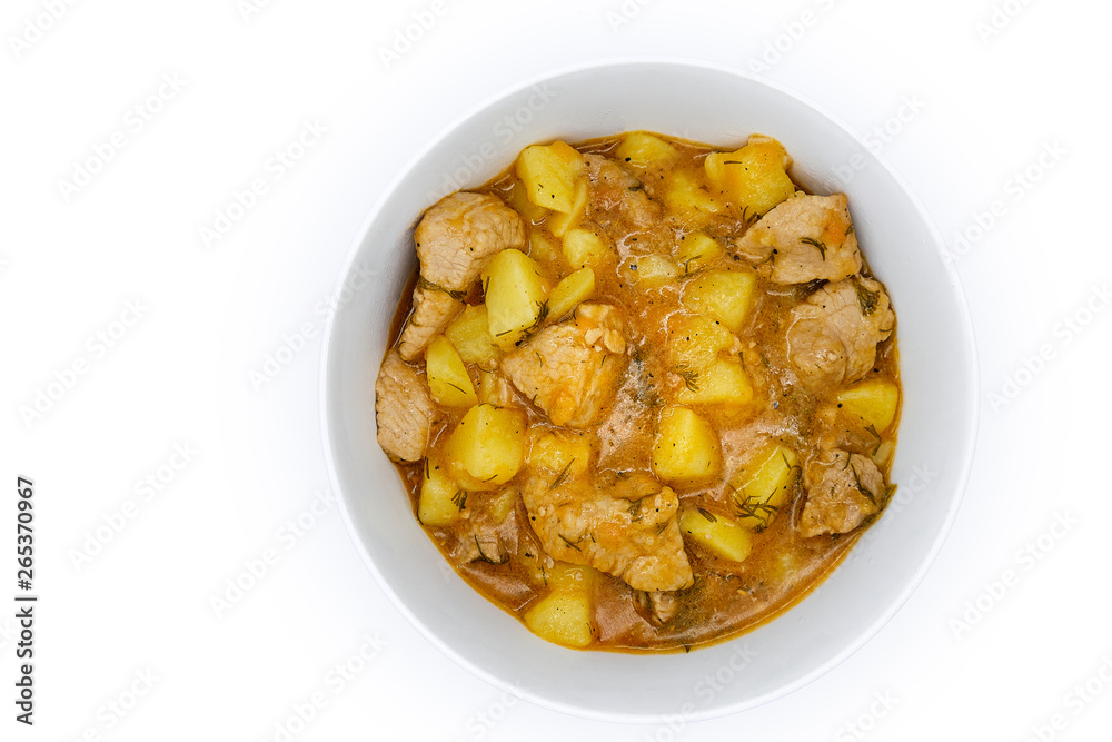 A plate of stewed and potatoes on isolated white background. Stirring with a spoon of meat and broth, top view. Ragout of natural potatoes and meat.