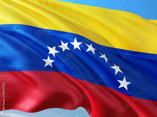 Flag of Venezuela waving in the wind against deep blue sky. High quality fabric.