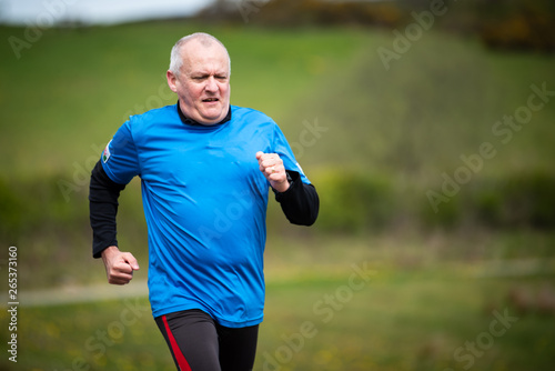 Senior man in 60s exercising and keeping fit by running in a park
