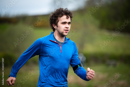 Young man in mid 20s exercising and keeping fit by running in a park
