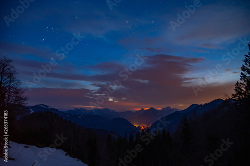 Sunset with stars and a city in the mountains