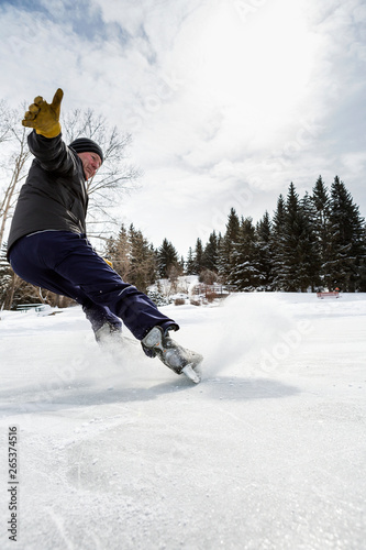 Male Gliding To A Stop On Skates With Ice Spray; Calgary, Alberta, Canada