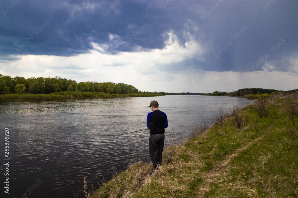 Fisherman fishes spinning on the river bank