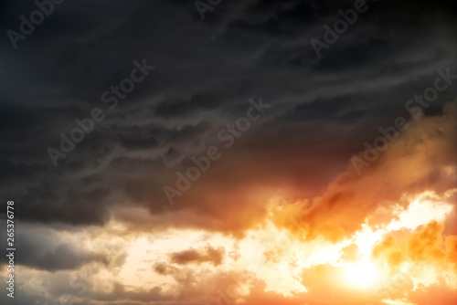 Beautiful dark fluffy cloudy sky with sun rays. Sunset light.