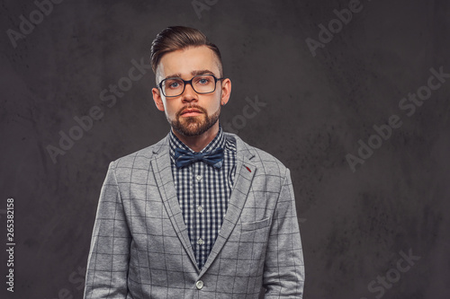 Studio shoot of smart attractive man in checkered blazer, glasses and shirt with bow.