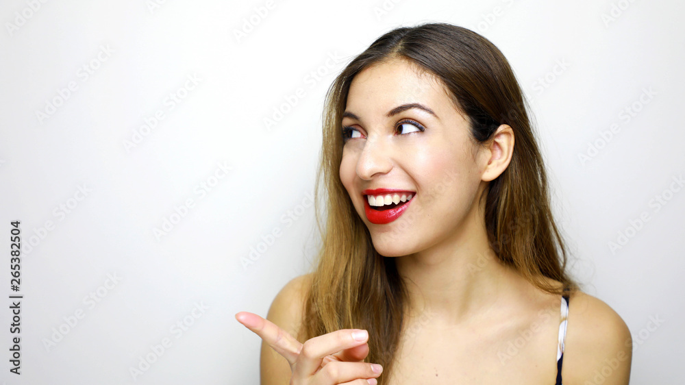 Beautiful woman looking to the side and pointing with finger to empty copy space isolated over white background Beautiful woman looking to the side and pointing with finger to empty copy space isolated over white background
