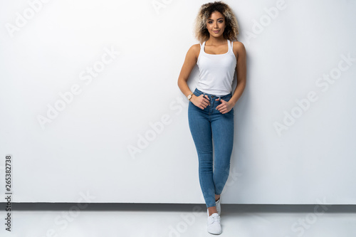 Full length portrait of stylish young black woman standing on white background.