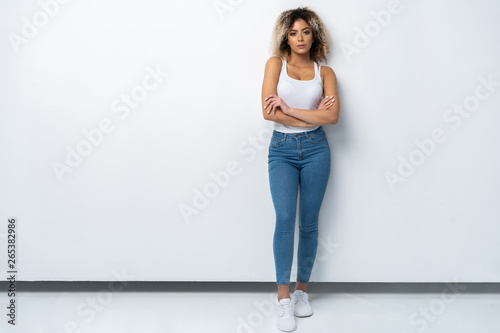 Full length portrait of stylish young black woman standing on white background.