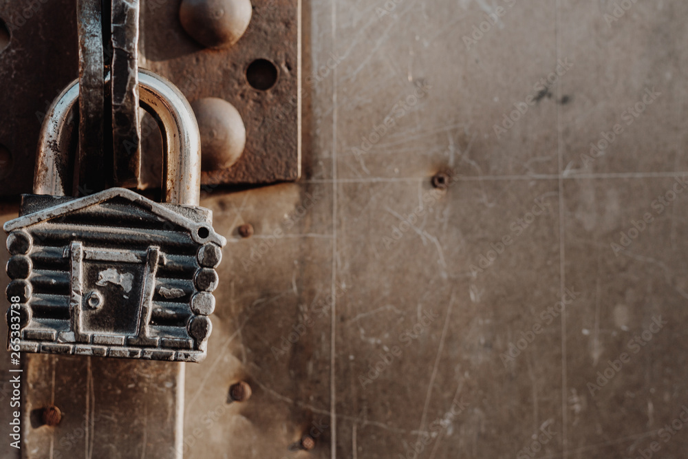 Padlock in the form of a hut hangs on the hinges of the closed gate. Metal gates. Padlock in the form of a hut hangs on the hinges of the closed gate. Metal gates.