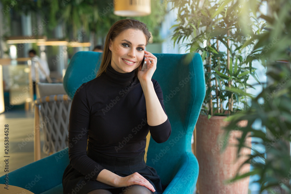 beautiful stylish girl sitting in a chair talking on the phone in the interior beautiful stylish girl sitting in a chair talking on the phone in the interior