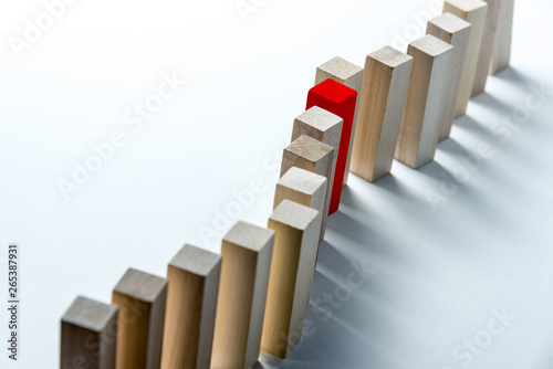 A long curved line of wooden cubes with one red  as a symbol of a queue  competition for a position or team  on a uneven white background. Horizontal frame