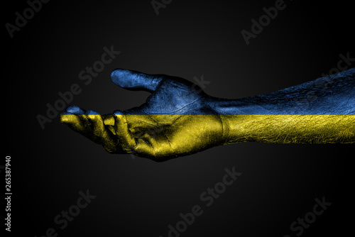 Outstretched hand with a drawn Ukraine flag, a sign of help or a request, on a dark background