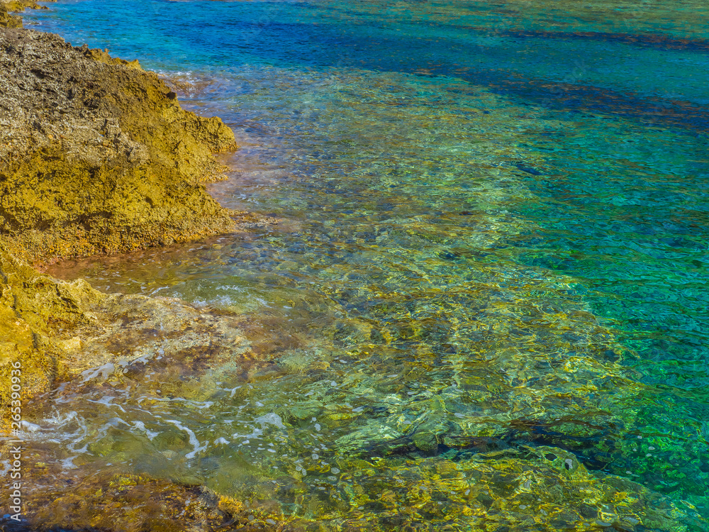 Extremely clear shallow water on small rocky beach in Crete, Greece