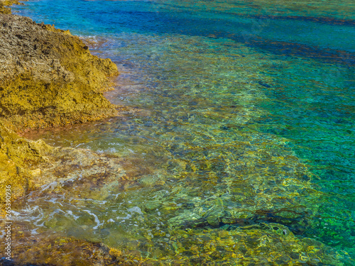 Extremely clear shallow water on small rocky beach in Crete, Greece