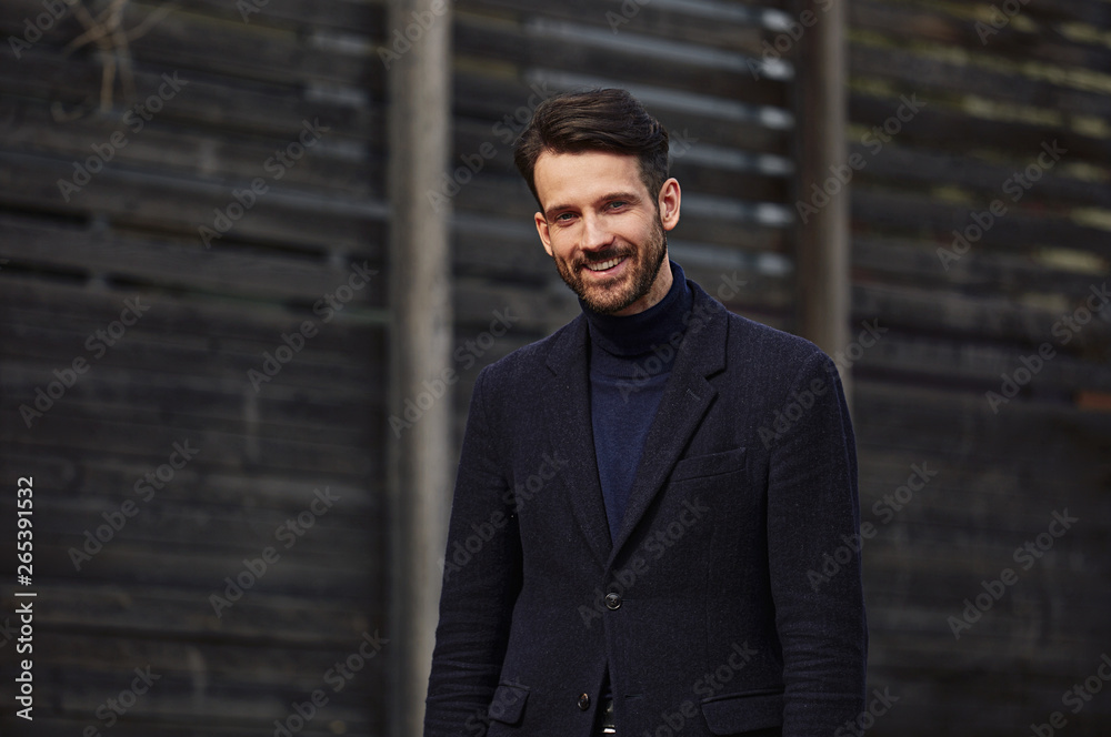 Fashion beard style business handsome male model posing in style clothing blue jacket and trousers on street wooden wall outdoors background. Closeup Fashion beard style business handsome male model posing in style clothing blue jacket and trousers on street wooden wall outdoors background. Closeup