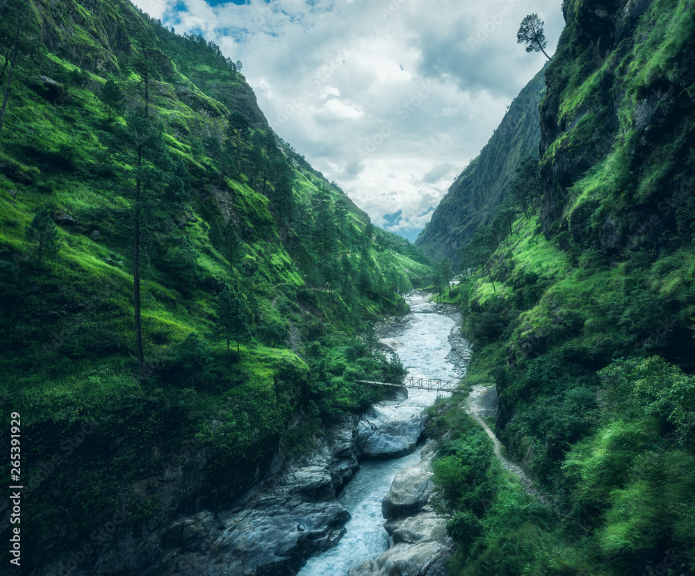 Beautiful mountains covered green grass. Moody landscape with mountain valley, river, waterfall, meadows and forest, sky with clouds in summer in Nepal in overcast day. Travel in Himalayas. Nature