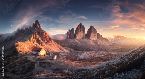 Mountain valley with beautiful house and church at sunset in spring. Landscape with buildings, high rocks, colorful sky, clouds, sunlight. Mountains in Tre Cime park in Dolomites, Italy. Italian alps