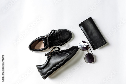 black shoes, purse and sunglasses with black lenses on a light background