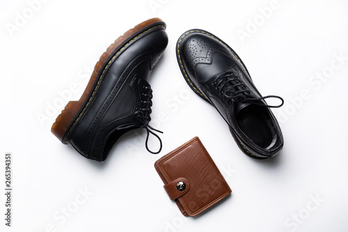 Photographie black leather derby shoes with polyurethane soles and a brown purse with a butto