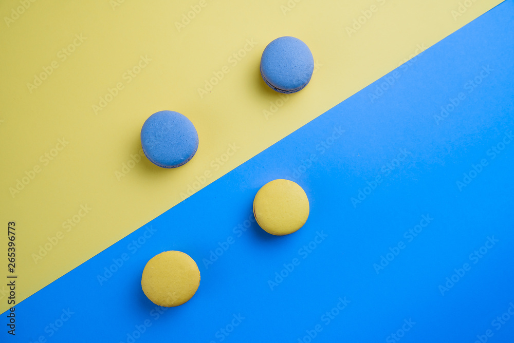 Sweet tasty blue and yellow french macaron cakes on yellow and blue background. Sweet tasty blue and yellow french macaron cakes on yellow and blue background.