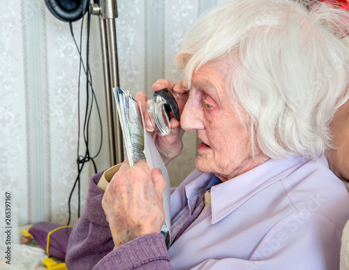 Visually impaired elderly woman with magnifyer photo