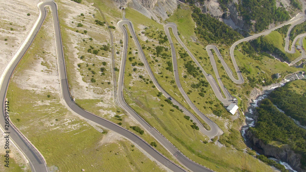 AERIAL: Flying above a scenic switchback road leading up to a mountain pass. - obrazy, fototapety, plakaty 