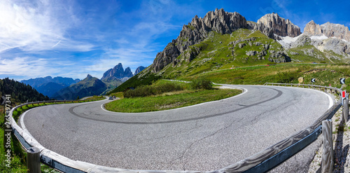 Tourists in cars drive away from the sharp hairpin turn in the sunny mountains. photo