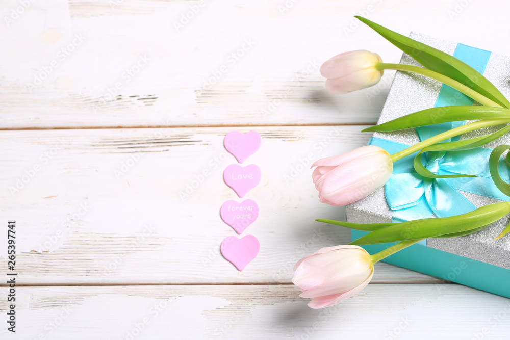 pink tulips on a gift box on a white wooden table pink tulips on a gift box on a white wooden table